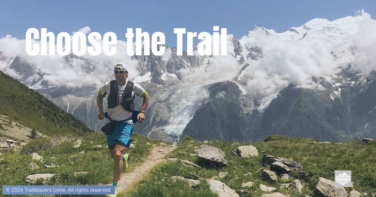 Runner moving along a narrow mountain trail surrounded by peaks, representing intentional direction and commitment to the path forward.